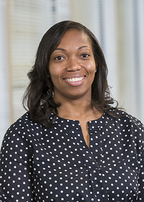 Corporate photo of Candis Polite from the waste up, wearing a navy blue and small white polka-dot top.
